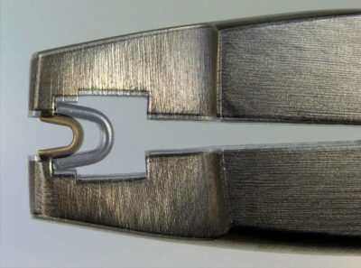 A large and a small zipper top stop correctly placed in Osborne pliers (photo composition)